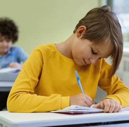 young boy sitting at desk working hard in classroom